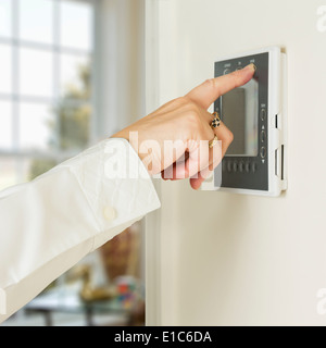 Utilizzando un elettronici digitali di ventilazione e riscaldamento termostato timer sul muro di una casa moderna Foto Stock