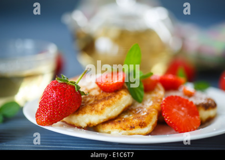 Ricotta frittelle fritte con lo zucchero e le fragole su una piastra Foto Stock