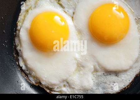 Foto macro di due uova strapazzate in nero padella Foto Stock
