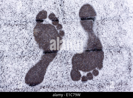 Due opposti a piedi nudi Impronte sulla neve in inverno Foto Stock
