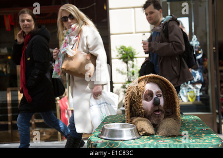 Street performer agisce come un divertente cane in un cestello. Il Covent Garden nel West End di Londra, Regno Unito. Foto Stock