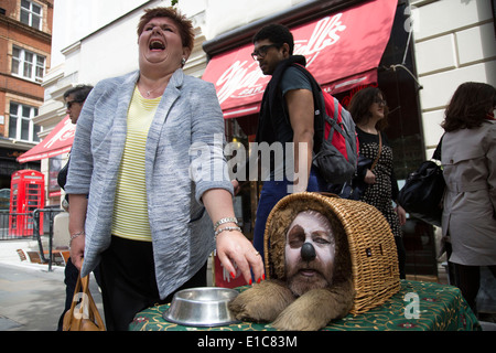 Street performer agisce come un divertente cane in un cestello. Il Covent Garden nel West End di Londra, Regno Unito. Foto Stock