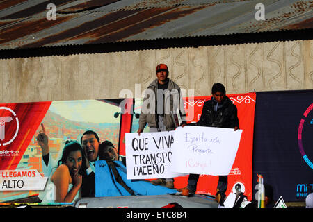 La Paz in Bolivia. Il 30 maggio 2014. Gli spettatori cartelloni attesa come stanno di fronte una palizzata durante la cerimonia di inaugurazione di sistema della cabinovia che collega La Paz e El Alto. Credito: James Brunker / Alamy Live News Foto Stock