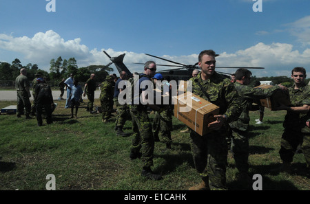 Soldati canadesi, U.S. I marinai e i cittadini haitiani offload di cibo e di acqua da un MH- 53E mare Dragon elicottero da Helicopt Foto Stock