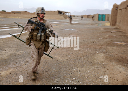 Un marine statunitense con il Primo Battaglione, 7° Reggimento Marine, corre per fornire una scaletta di combattimento a un compagno di ricerche marine un composto 16 maggio 2014 nel villaggio di Larr, provincia di Helmand, Afghanistan. Foto Stock