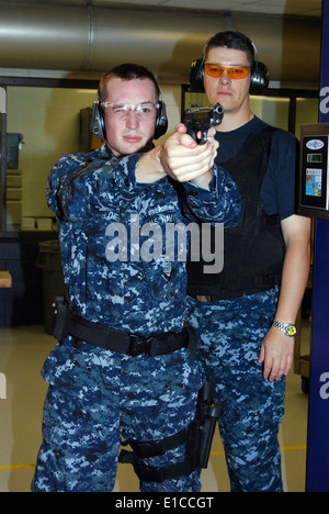 Stati Uniti Navy Gunner?s mate 1. Classe Kenneth Matthews incendi a 9 mm a pistola simulatore come Fire Controlman 1a classe Daniel Valenzue Foto Stock