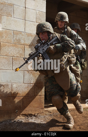 Stati Uniti Marine Corps Sgt. Possibilità Walsch, sinistra, e Lance Cpl. Russell Stine uscire da un edificio con la loro M-4 carabina fucili a Schof Foto Stock