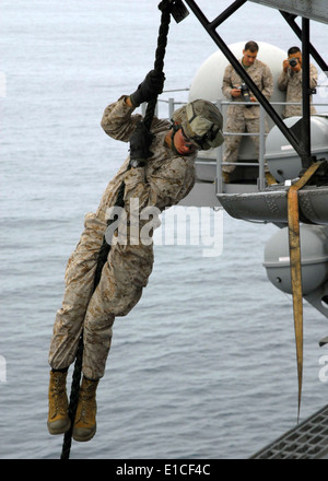 Un U.S. Marine assegnato all'undicesimo Marine Expeditionary Unit fast-corde out statico di un CH-46E Sea Knight elicottero a bordo Foto Stock