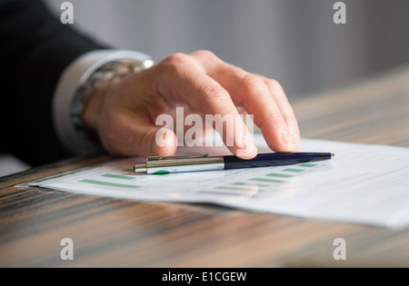 Uomo con le mani in mano in possesso di una penna nera in entrambe le braccia in un gesto di pensiero durante una riunione o negoziazione Foto Stock