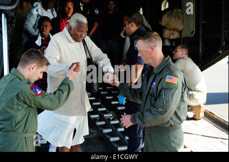 Stati Uniti Air Force Capt. Philip Noland, sinistra e Tech. Sgt. Brian Gand aiutare un anziano terremoto di Haiti superstite verso il fondo della rampa Foto Stock