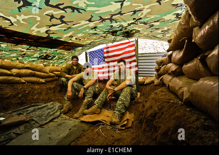 Da sinistra, U.S. Army Spc. Charles Henderson, PFC. Collen Pozzi e SPC. Marshall Hodge ha sedersi dentro un rifugio improvvisato decorat Foto Stock