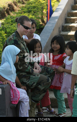 Un U.S. Navy Seabee assegnato alla Joint Special Operations Task Force - Filippine colloqui con i bambini durante un nastro-ce di taglio Foto Stock