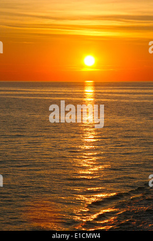 Beautiful golden arancione tramonto sull'oceano. Il sole tramonta ruotando il cielo giallo, arancio e toni rossi & riflette nell'oceano. Foto Stock