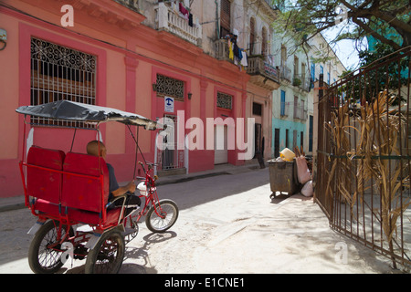 Bicicletta cubano taxi driver prendendo una pausa in una strada tranquilla nel centro storico, l'Avana Foto Stock