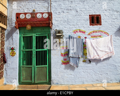 India Rajasthan, Jaisalmer, lavaggio e asciugatura sulla linea fuori, blu dipinto di casa con la porta verde Foto Stock