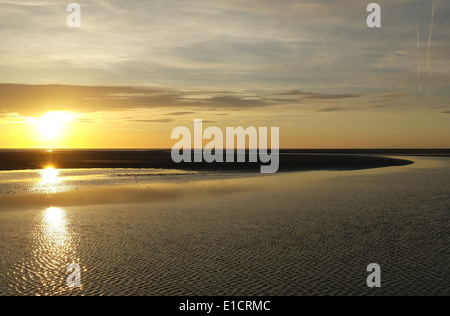 Il giallo sole sotto grigio arancione tramonto nuvole splendente e riflettendo sulla sabbia bagnata increspature Beach, St Annes, costa di Fylde, Regno Unito Foto Stock