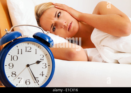 Insonnia, orologio a notte. La donna non riesce a dormire. Foto Stock