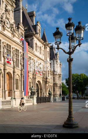 Andare in bicicletta passato Hotel de Ville vicino al tramonto, Parigi Francia Foto Stock