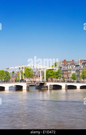 Il Magere Brug ('Skinny ponte") di Amsterdam lungo il fiume Amstel su una bella giornata di sole Foto Stock