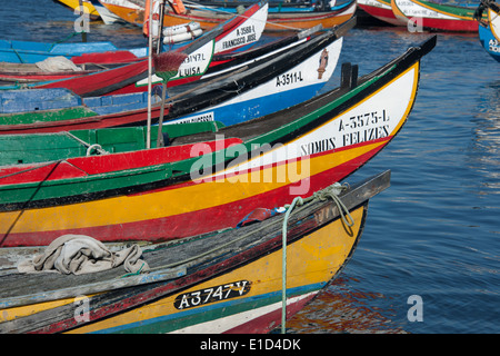 Moliceiros tradizionali barche da pesca con alta prows, dipinte in colori vivaci, ormeggiata offshore Torreira a. Foto Stock