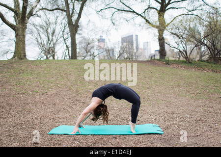 Una giovane donna in Central Park, in un nero leotard e gambali, fare yoga. Foto Stock