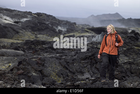 Donna escursionismo attraverso il campo di lava al vulcano Krafla / Nord Islanda Foto Stock