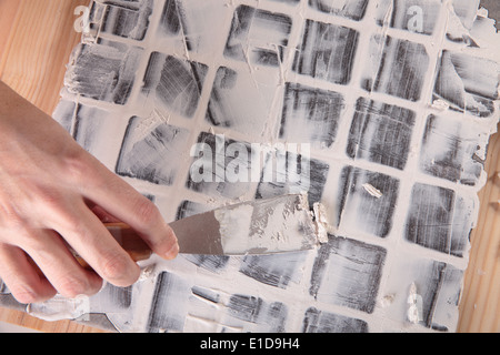 Lavoratore si applica boiacca a piastrelle grigie Foto Stock