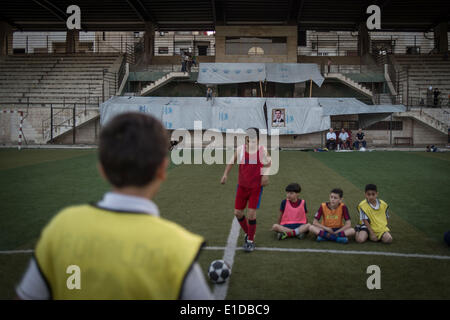 Damasco, Siria. 31 Maggio, 2014. Ragazzi siriano treno in un campo di calcio dove un poster del candidato presidenziale Bashar al-Assad è visto in Damasco Capitale della Siria, il 31 maggio 2014, in vista delle prossime elezioni presidenziali del 3 giugno. Credito: Pan Chaoyue/Xinhua/Alamy Live News Foto Stock