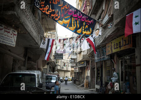 Damasco, Siria. 31 Maggio, 2014. Un ragazzo siriano passeggiate in una corsia dove manifesti del candidato presidenziale Bashar al-Assad e della Siria bandiere nazionali sono visti in Damasco Capitale della Siria, il 31 maggio 2014, in vista delle prossime elezioni presidenziali del 3 giugno. Credito: Pan Chaoyue/Xinhua/Alamy Live News Foto Stock