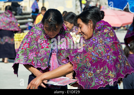 Due Tzotzil donne indiane ispezione brochure tessili domenica mercato San Lorenzo Zinacantan Village in Chiapas Foto Stock