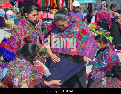 Tzotzil donne indiane di ispezionare i prodotti tessili domenica mercato San Lorenzo Zinacantan Village in Chiapas Foto Stock