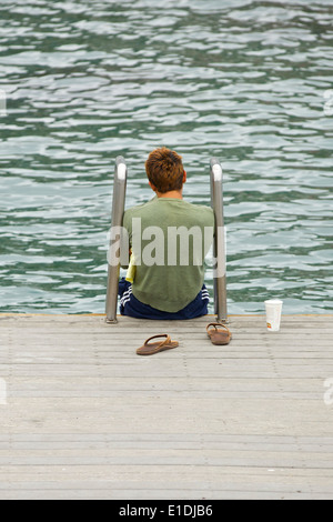 Giovane uomo seduto dall'acqua di Avalon, Isola di Santa Catalina, California. Foto Stock
