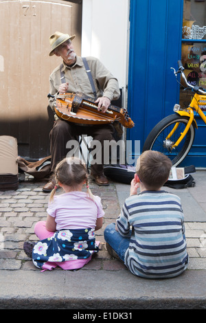 Un suonatore ambulante a Rochester spazza Festival 2014 con due bambini che guardano a lui e ascolto di lui Foto Stock