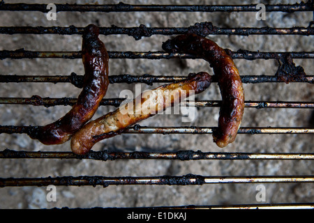 Tre bruciato salsicce sulla griglia per il barbecue Foto Stock