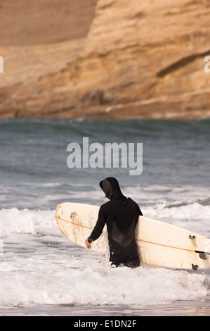 Maschio adulto capi in mare per una sessione di surf Foto Stock