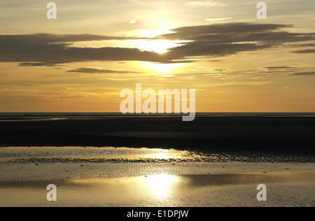 Bianco sole riflettendo sulla sabbia bagnata increspature spiaggia al di sotto del cielo giallo tramonto dietro le nuvole grigie, St Annes, costa di Fylde, Regno Unito Foto Stock