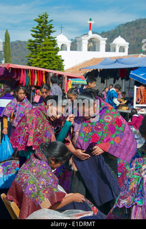 Tre Tzotzil donne indiane di ispezionare i prodotti tessili domenica mercato San Lorenzo Zinacantan Village Chiapas Foto Stock