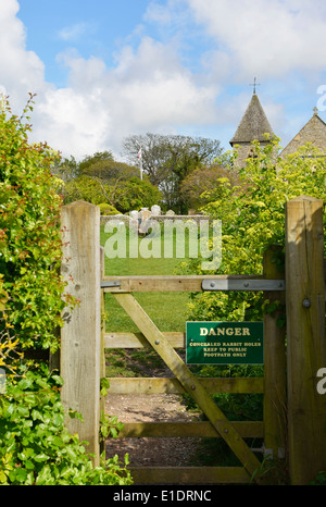 Sentiero con gate attraverso Snow Hill Roulotte con la chiesa di San Pietro e di San Paolo in distanza, West Wittering,Sussex, Regno Unito Foto Stock