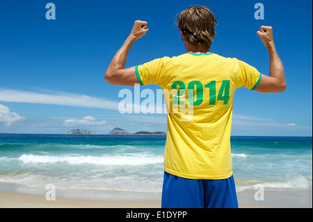 Uomo brasiliano nel 2014 shirt in team Brazil celebra i colori sulla tropicale sulla spiaggia di Ipanema di Rio de Janeiro Foto Stock