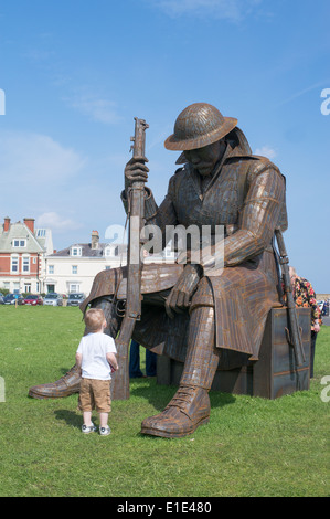 Un giovane bambino guardando Tommy un acciaio corten scultura di WW1 soldato da Ray Lonsdale, Seaham Harbour North East England, Regno Unito Foto Stock