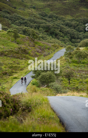 Coppia di ciclisti cavalcare un percorso attraverso la campagna sull'Isola di Skye Foto Stock