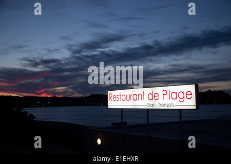 Un ristorante segno illuminata dal sole che tramonta sulla città di Calvi, in Corsica. Foto Stock
