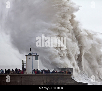 Decine di persone pack mura sul mare a Porthcawl nel Galles del Sud per guardare le massicce ondate di colpire il faro Foto Stock