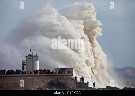 Decine di persone pack mura sul mare a Porthcawl nel Galles del Sud per guardare le massicce ondate di colpire il faro Foto Stock