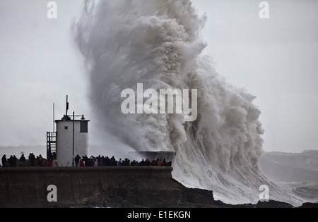 Decine di persone pack mura sul mare a Porthcawl nel Galles del Sud per guardare le massicce ondate di colpire il faro Foto Stock