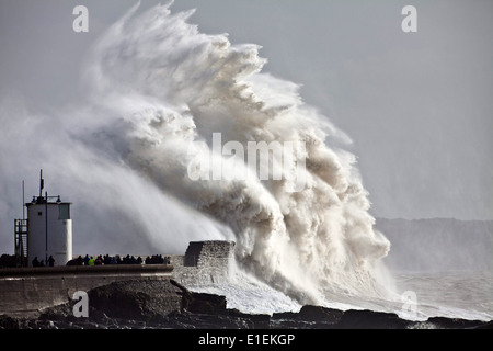 Decine di persone pack mura sul mare a Porthcawl nel Galles del Sud per guardare le massicce ondate di colpire il faro Foto Stock