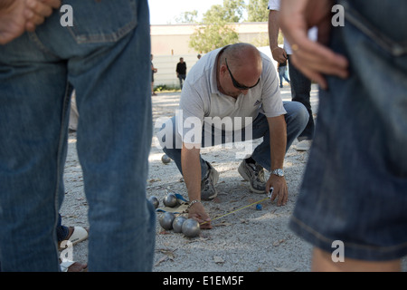 Un uomo di misurare distanze durante una partita a bocce in città di Calvi, in Corsica. Foto Stock