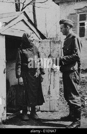 La foto di un comunicato stampa nazista mostra un soldato tedesco che parla con un residente nativo sul fronte orientale nel maggio 1942. Il testo originale della propaganda sul retro del quadro recita: "I soldati sono in grado di trovare la loro posizione in tutti i paesi e in tutte le lingue. Qui, un soldato tedesco negozia con un agricoltore ucraino." Fotoarchiv für Zeitgeschichtee - NESSUN SERVIZIO DI CABLAGGIO Foto Stock