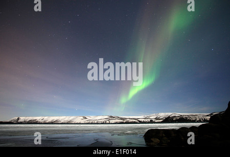 Le luci del nord brillano al di sopra di un lago ghiacciato al di fuori di Reykjavik in Islanda Foto Stock