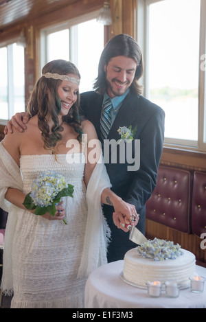 Boho giovane riducendo la torta di nozze all'interno di un battello fluviale Foto Stock